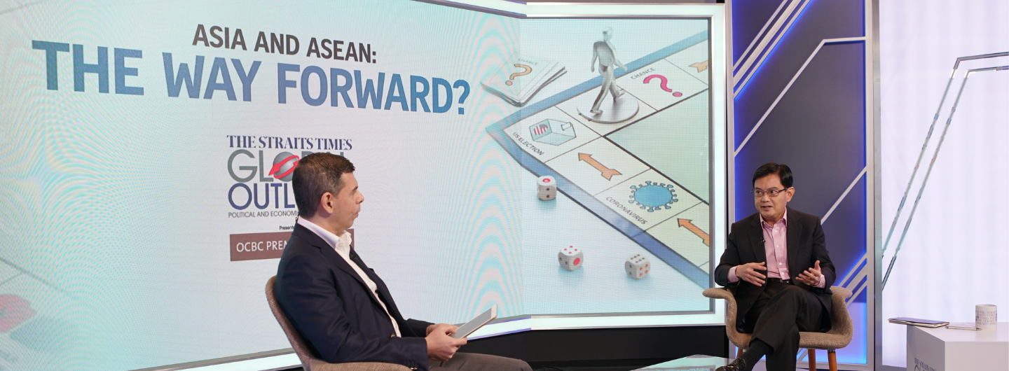 Two men sit in chairs on a set. Behind them is a screen displaying "Asia and ASEAN: The Way Forward?"